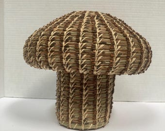 May include: A woven mushroom-shaped basket made of natural materials, with a brown and tan color scheme.