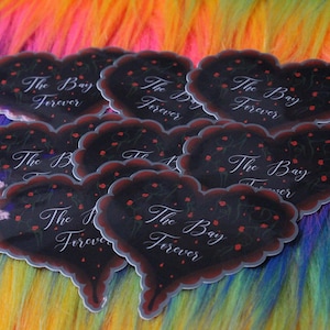May include: A set of seven black heart-shaped stickers with the text "The Bay Forever" in white cursive lettering. The stickers have a glossy finish and are decorated with red flower accents.