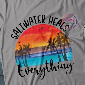 K&ouml;nnte beinhalten: Ein graues T-Shirt mit einem Sonnenuntergangs-Motiv und dem Text "Saltwater Heals Everything".