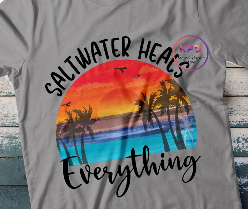 K&ouml;nnte beinhalten: Ein graues T-Shirt mit einem Sonnenuntergangs-Motiv und dem Text "Saltwater Heals Everything".