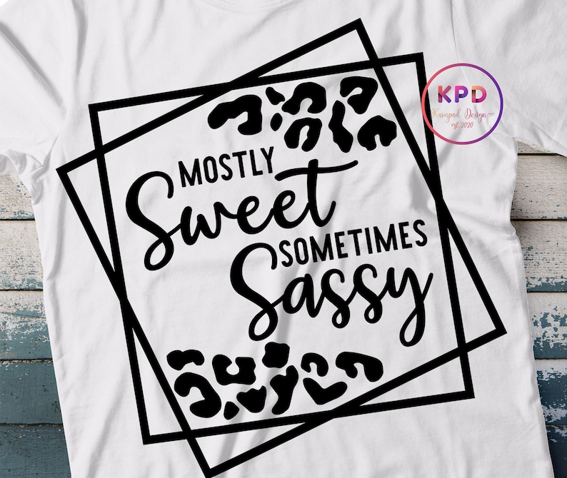 Puede incluir: Dise&ntilde;o gr&aacute;fico en blanco y negro con un patr&oacute;n de estampado de leopardo. El texto dice "Mostly Sweet Sometimes Sassy" dentro de un marco cuadrado doble negro.