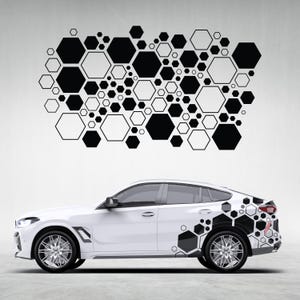 May include: A white car with a black and white geometric hexagon pattern on the side and rear. The design features various sizes of black hexagons, some outlined in white, creating a modern, abstract aesthetic. The car has silver rims.