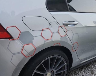 May include: Silver car with a geometric design of red and gray hexagons. The design is on the side panel of the car, near the rear tire. The car has a black tire and a silver rim.