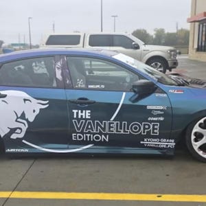 May include: A blue and teal car with white graphics, including a bull and the text "THE VANELLOPE EDITION." Additional text includes "KYOHO GRADE VANELLOPE.FCI" and "COMETIC." A character graphic is visible in the window.