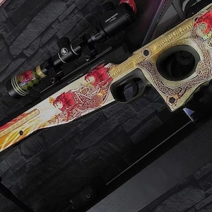 Op de afbeelding: Een aangepast luchtgeweer met een gemonteerde richtkijker. Het geweer heeft een wit en goud ontwerp met rode drakenillustraties en ingewikkelde patronen. De richtkijker is zwart met groene en rode accenten.