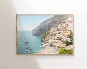 May include: A framed photograph of a coastal town built into a cliffside. The town is a mix of white and yellow buildings with a blue sea in the foreground. The photo is taken from a high vantage point, looking down at the town.