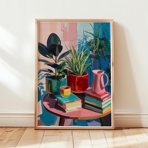 May include: A framed art print depicting a round pink table holding a green potted rubber plant, a spiky plant in a red pot, a small yellow cup, a pink pitcher, and two stacks of colorful books against a light pink and blue wall background.