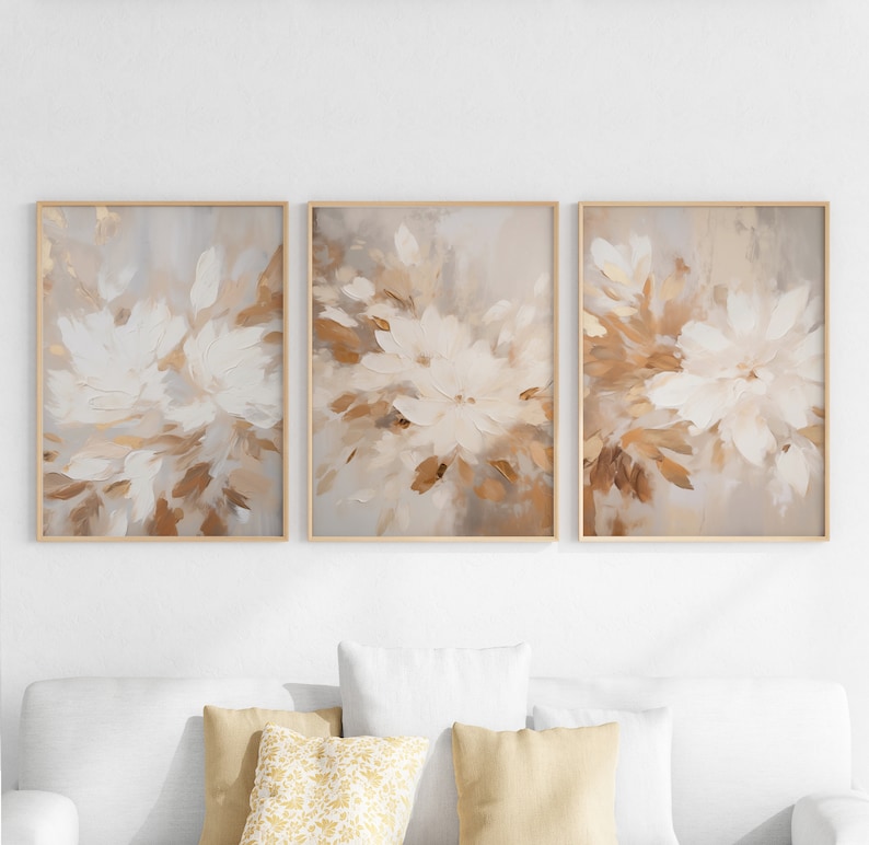 May include: A set of three abstract art prints featuring a muted brown and white floral design. The prints are framed in a light wood frame.