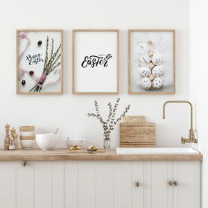 May include: Three framed prints with Easter-themed designs. The left print features a bouquet of pussy willow branches with a pink ribbon and the text "Happy Easter". The center print features the text "Happy Easter" in a stylized font. The right print features a white bunny rabbit with a nest of white eggs decorated with black ink.