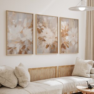 May include: Three framed abstract paintings with a muted color palette of beige, brown, and white. The paintings feature a floral design with brushstrokes that create a textured effect.