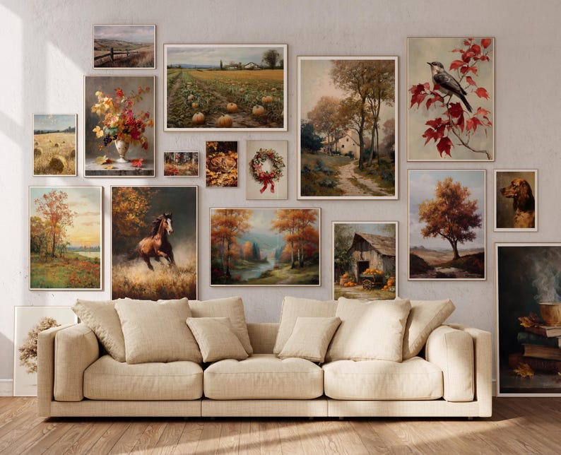 May include: A collection of framed vintage-style landscape and still-life paintings in warm autumnal tones. The artwork includes scenes of fields, trees, a horse, and a bird, arranged above a beige sofa.