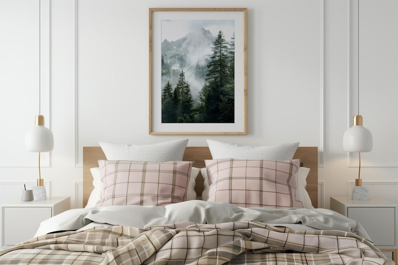 May include: A bedroom with a bed with a pink and brown plaid duvet cover and a framed photograph of a mountain scene with trees and fog.