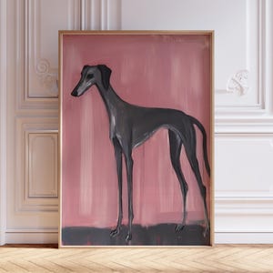 Puede incluir: Pintura abstracta de un galgo en posici&oacute;n de pie. El perro est&aacute; pintado en tonos grises sobre un fondo rosa con una base gris oscuro. La obra de arte est&aacute; enmarcada en un marco de color dorado.