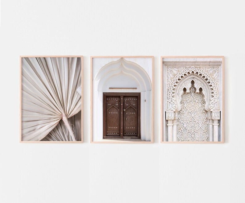 May include: Three framed prints with a minimalist aesthetic. The left print features a close-up of a beige palm leaf. The centre print shows a white archway with a wooden door. The right print shows a white archway with intricate carvings.