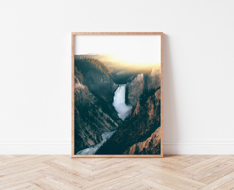 May include: A framed photograph of a waterfall cascading down a rocky cliffside, surrounded by lush green trees. The sun is shining brightly in the background, creating a warm glow over the scene.