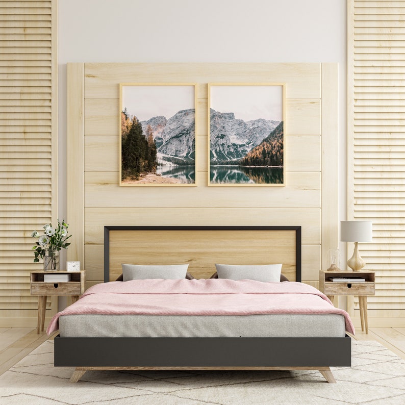 May include: A bedroom with a wooden headboard and two framed landscape photos above the bed. The bed has a gray duvet and pink blanket. There are two nightstands with lamps on either side of the bed.