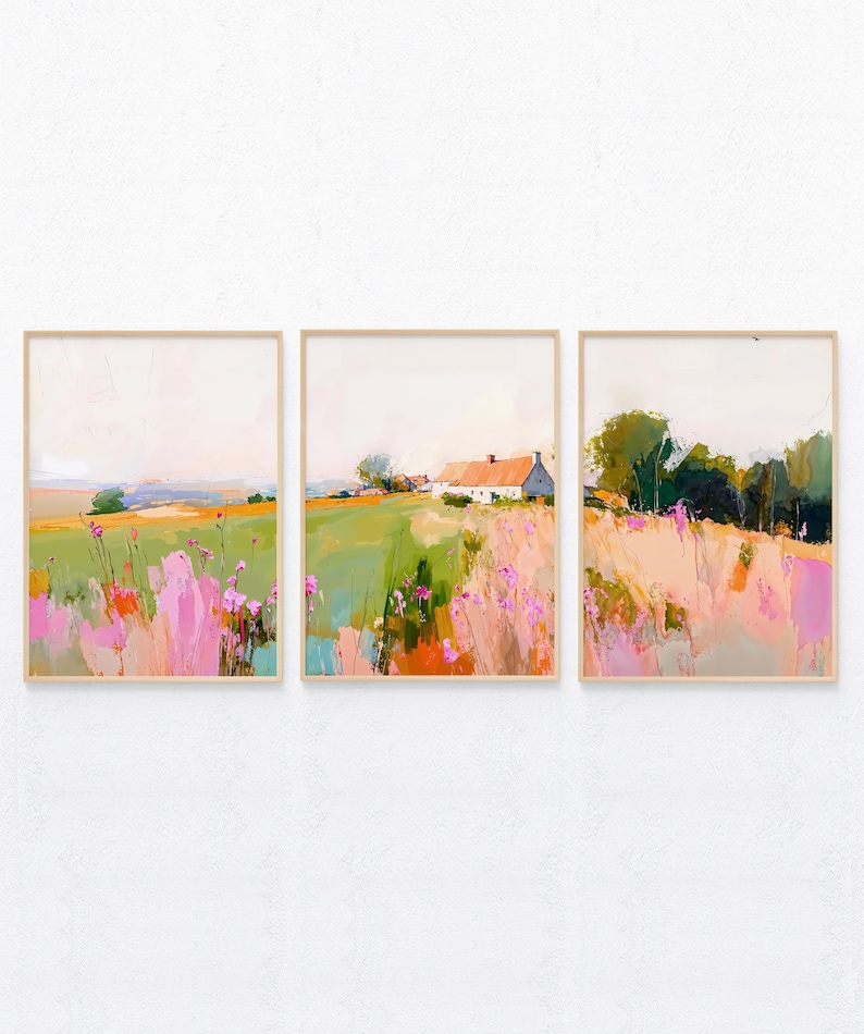May include: A set of three framed wall art prints featuring a continuous landscape painting. The artwork displays a rural scene with a white farmhouse, green fields, and vibrant pink wildflowers under a soft, pale sky, all encased in light wood frames.
