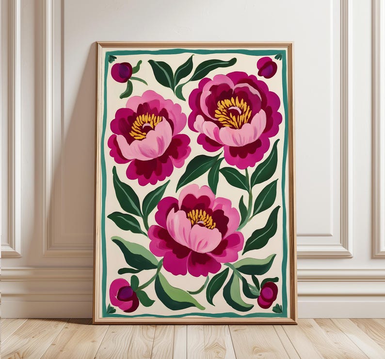 May include: A framed print featuring a floral design with three pink and magenta peonies on a cream background. The peonies have yellow centers and are surrounded by green leaves. The frame is a light wood color with a teal border.