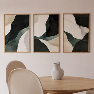 May include: Three framed abstract art prints with a minimalist design featuring black, white, and green watercolor shapes.