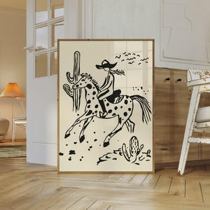 May include: Black and white illustration of a person riding a spotted horse in a desert landscape. The person is wearing a cowboy hat and the horse is galloping. There are cacti and birds in the background.