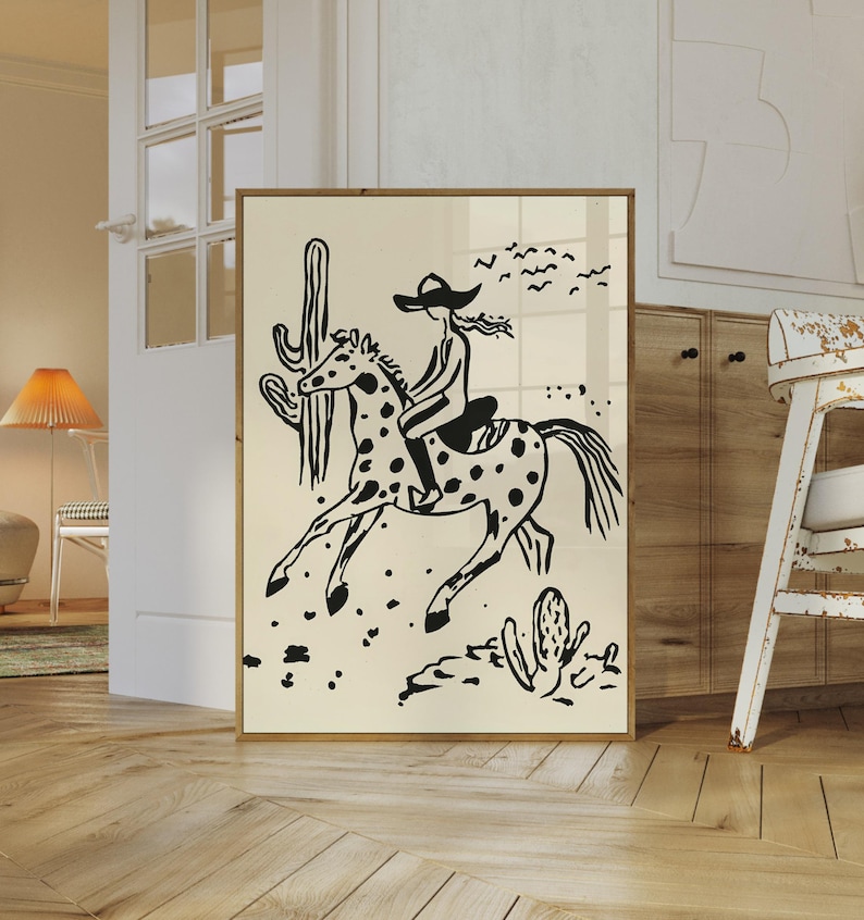 May include: Black and white illustration of a person riding a spotted horse in a desert landscape. The person is wearing a cowboy hat and the horse is galloping. There are cacti and birds in the background.