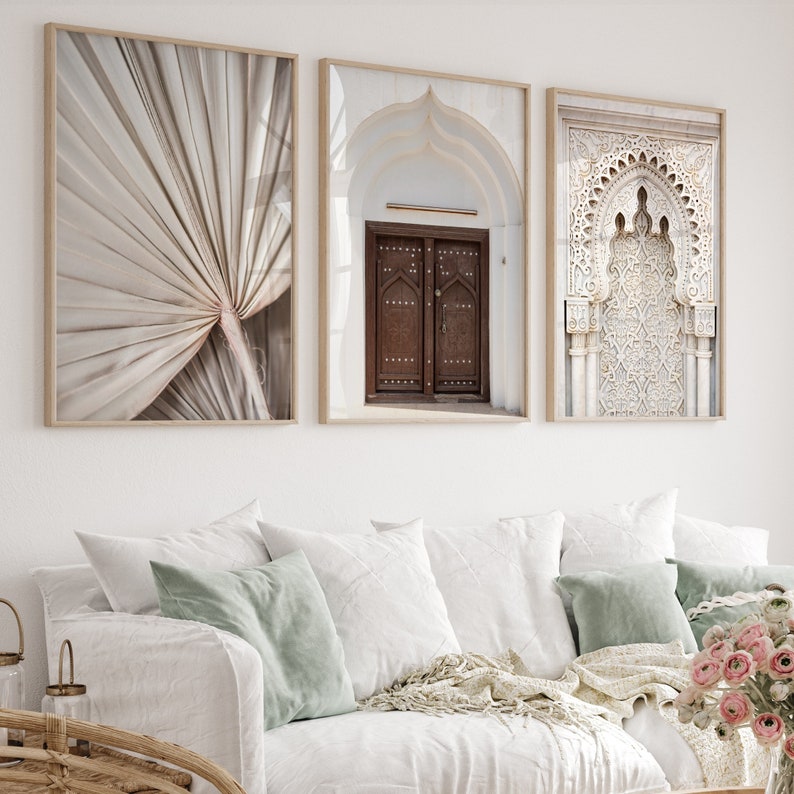May include: Three framed prints with a Moroccan theme. The left print features a close-up of a beige palm leaf. The centre print shows a white archway with a brown wooden door. The right print shows a white archway with intricate carvings.