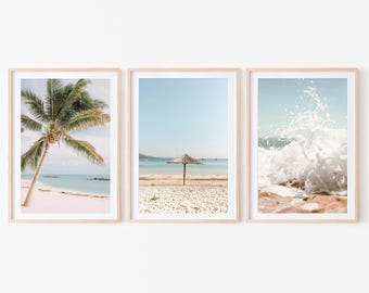 May include: A set of three framed prints depicting beach scenes. The first print shows a palm tree on a white sandy beach with turquoise water. The second print shows a beach umbrella on a white sandy beach with turquoise water. The third print shows a wave crashing on a beach with white sand and turquoise water.