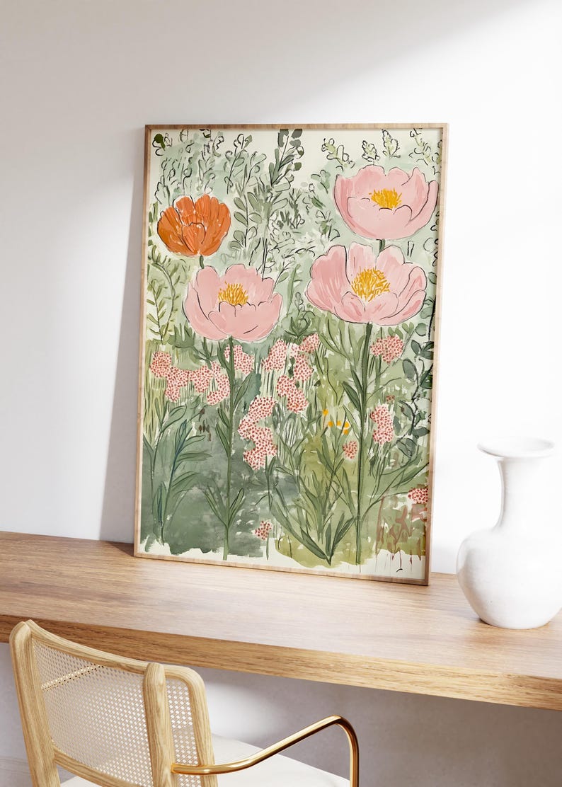 K&ouml;nnte beinhalten: Ein gerahmter Kunstdruck mit Blumenmotiven, der eine Aquarellmalerei von rosa und orangefarbenen Blumen mit gelben Zentren vor einem Hintergrund aus gr&uuml;nem Laub zeigt. Das Kunstwerk wird auf einer Holzoberfl&auml;che ausgestellt, mit einer wei&szlig;en Vase und einem Stuhl im Hintergrund.