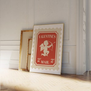 May include: A vintage-style Valentine's Day mail stamp with a red background and a white cherub holding a bow and arrow. The stamp says "Valentine's 2&cent; Mail 2&cent;".