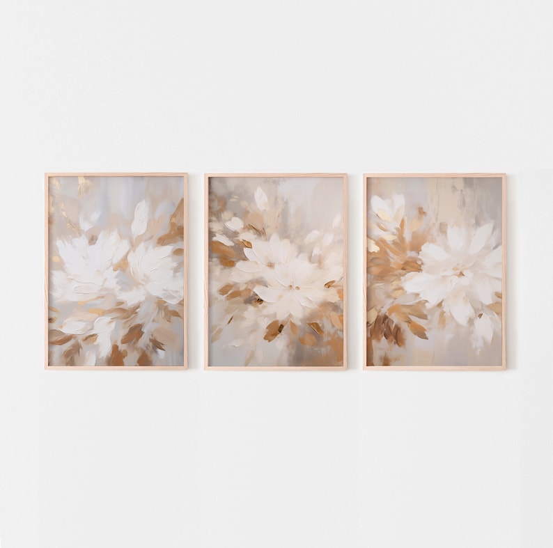 May include: A set of three framed abstract paintings with a floral theme. The paintings feature white and brown brushstrokes on a light gray background.