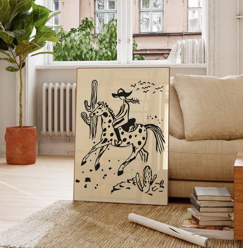 May include: Black and white illustration of a person riding a horse in a desert landscape. The person is wearing a hat and the horse has spots. There are cacti and birds in the background.