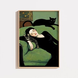 May include: A framed art print depicts a woman in a black dress reclining on a green sofa, with a tabby cat resting on her arm and a black cat lounging above. The artwork has a vintage aesthetic.