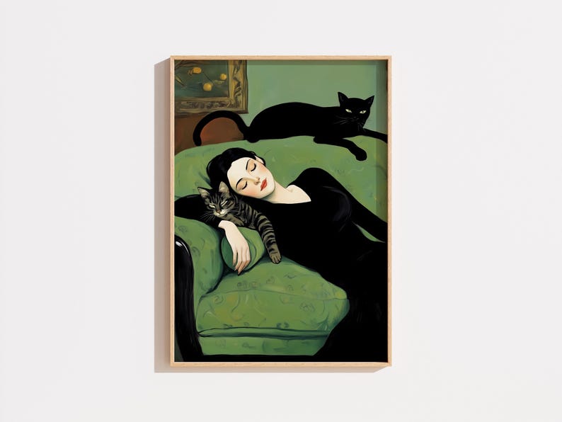 May include: A framed art print depicts a woman in a black dress reclining on a green sofa, with a tabby cat resting on her arm and a black cat lounging above. The artwork has a vintage aesthetic.