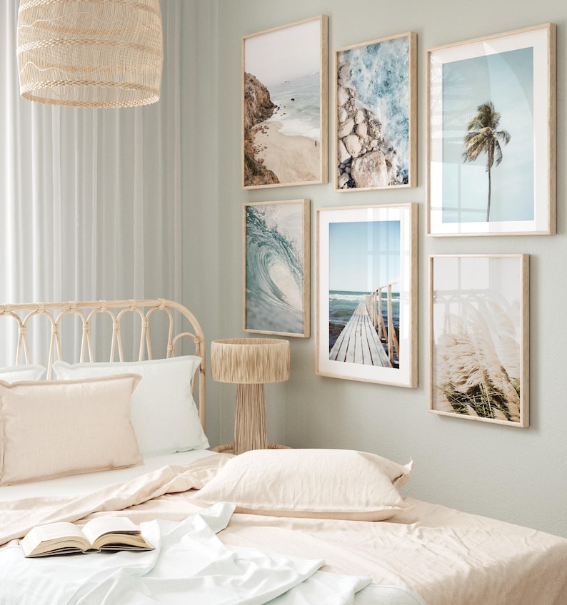 May include: A bedroom with a wicker headboard bed, white bedding, and a bedside table with a lamp. The walls are decorated with framed beach-themed prints.