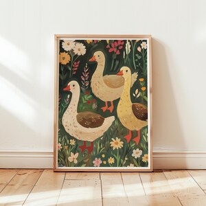 May include: A framed illustration of three geese in a field of flowers. The geese are white with brown markings and are standing in a field of green grass and colourful flowers. The background is a dark green.