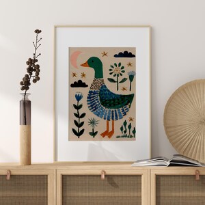 Puede incluir: Impresi&oacute;n art&iacute;stica enmarcada con una ilustraci&oacute;n caprichosa de un pato. El pato tiene la cabeza verde, el cuerpo azul y verde y las patas naranjas. El fondo es de color canela con elementos florales y celestiales. La obra est&aacute; enmarcada en oro.