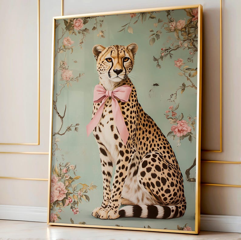 May include: A cheetah with a pink bow sitting in front of a floral background. The cheetah is looking directly at the viewer. The background is a light blue-green color with pink and white flowers.