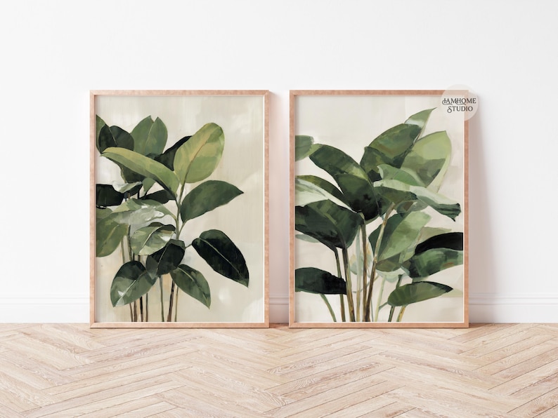 Puede incluir: Dos impresiones bot&aacute;nicas enmarcadas con plantas de hojas verdes. La obra de arte tiene un fondo beige claro y un marco de madera natural. Las impresiones se exhiben sobre un suelo de madera clara contra una pared blanca.