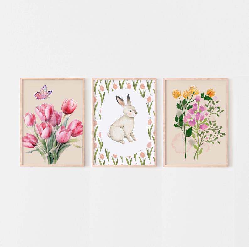 May include: Three framed prints with watercolor illustrations of flowers and a rabbit. The first print features a bouquet of pink tulips with a butterfly. The second print features a white rabbit sitting in a circle of pink tulips. The third print features a bouquet of pink and yellow flowers.