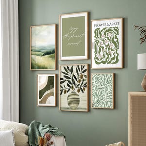 May include: A collection of six framed art prints with a nature theme. The prints feature landscape scenes, abstract designs, and botanical illustrations. One print reads "Enjoy the present moment." The color palette includes shades of green, brown, and white.