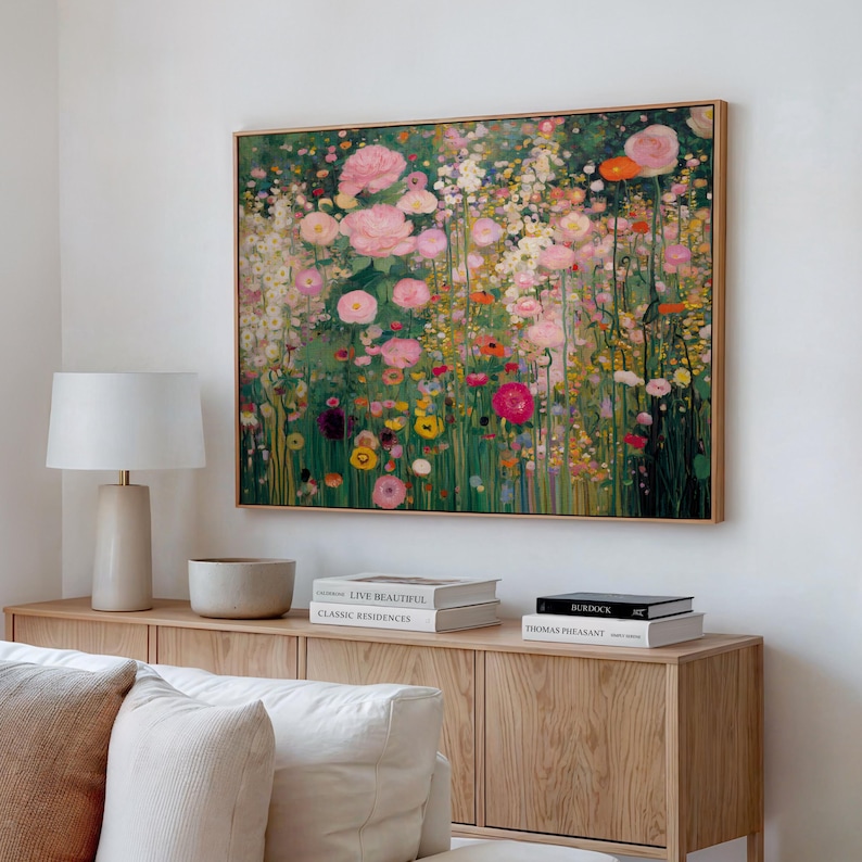 May include: A rectangular wall art print featuring a dense, impressionistic garden scene filled with pink, white, yellow, and red flowers against a deep green foliage background, framed in a light-toned wood border and displayed on a white wall.