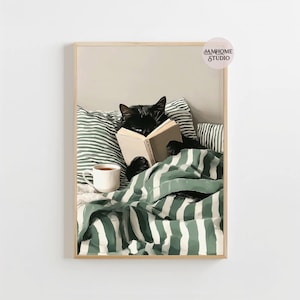 May include: A framed print featuring a black cat reading a book in bed. The cat is nestled under a green and white striped blanket, with a cup of coffee nearby. The print has a neutral color palette and a cozy, relaxed vibe.