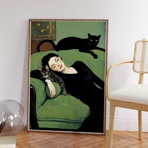 May include: Art print featuring a woman in a black dress reclining on a green sofa with two cats. One cat is resting on the sofa, and the other is lying on the woman. The artwork is framed in a wooden frame.