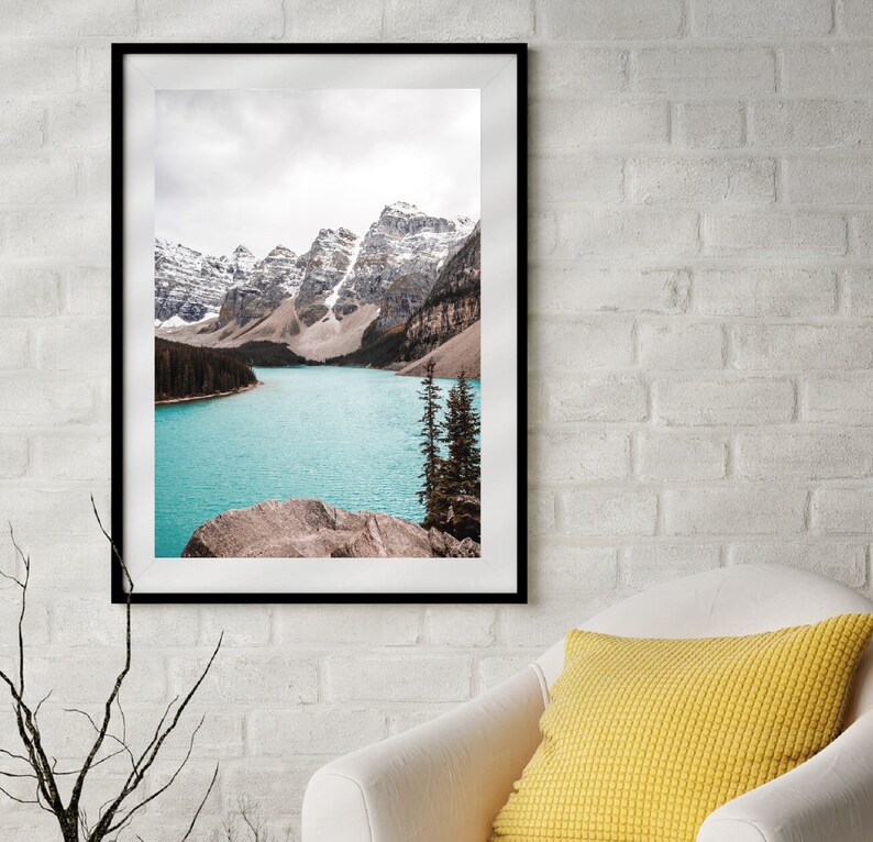 May include: A framed photograph of a mountain lake with snow-capped mountains in the background. The lake is a vibrant turquoise blue and the mountains are a soft brown and white.