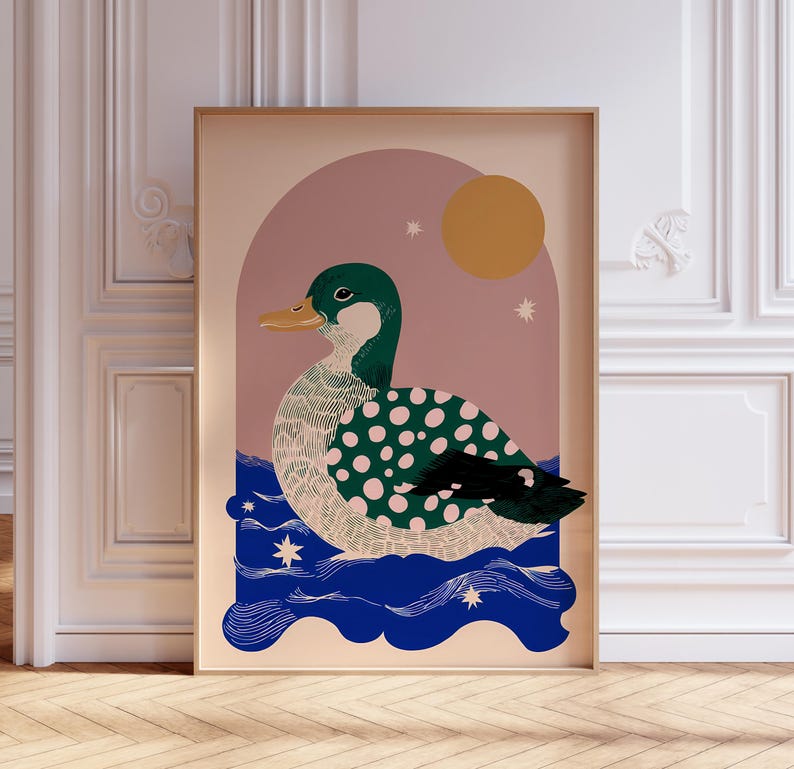 May include: A framed art print depicting a stylized duck. The duck has a green head and back with white polka dots, a yellow beak, and is set against a pink and blue background with a sun and stars.