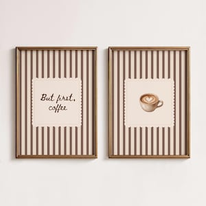 Puede incluir: Dos cuadros rectangulares con marcos finos de color bronce y fondo de rayas verticales marrones y beige. Una lámina muestra el texto "But first, coffee" en letra cursiva marrón oscuro, y la otra una taza de café con arte de corazón.