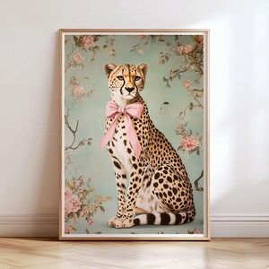May include: A cheetah with a pink bow sitting in front of a floral background. The cheetah is looking directly at the viewer.