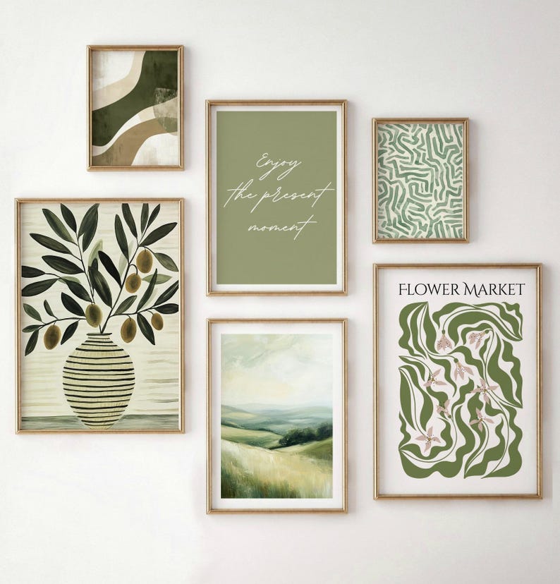 May include: A collection of six framed art prints with gold frames. The prints feature various designs, including abstract shapes, botanical illustrations, and landscape paintings. One print has the text "Enjoy the present moment" in cursive. Another print says "Flower Market".