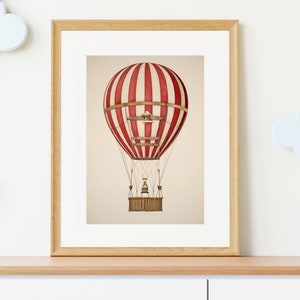 May include: A framed print of a red and white striped hot air balloon with a wicker basket. The balloon is floating in the air against a beige background.