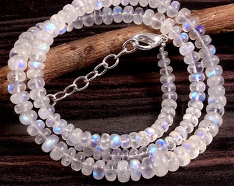 Op de afbeelding: Een witte maansteen ketting met een zilveren sluiting. De ketting is gemaakt van ronde kralen en heeft een iriserende glans.